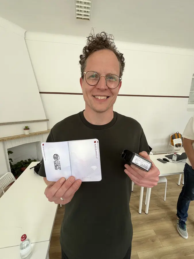 An attendee smiling and showing off Ruby on Waves swag